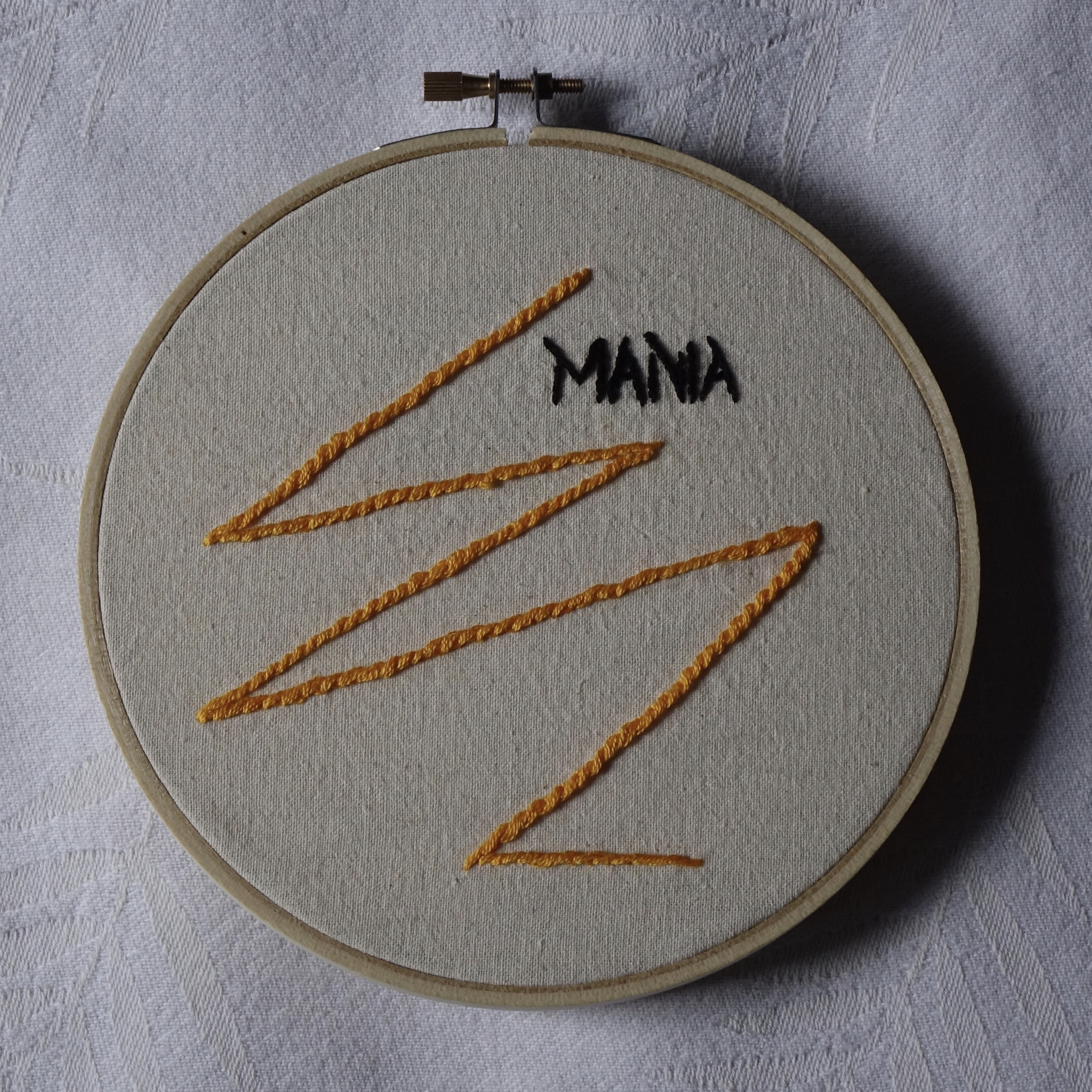 "MANIA" embroidered in black with an orange lightning bolt. 
